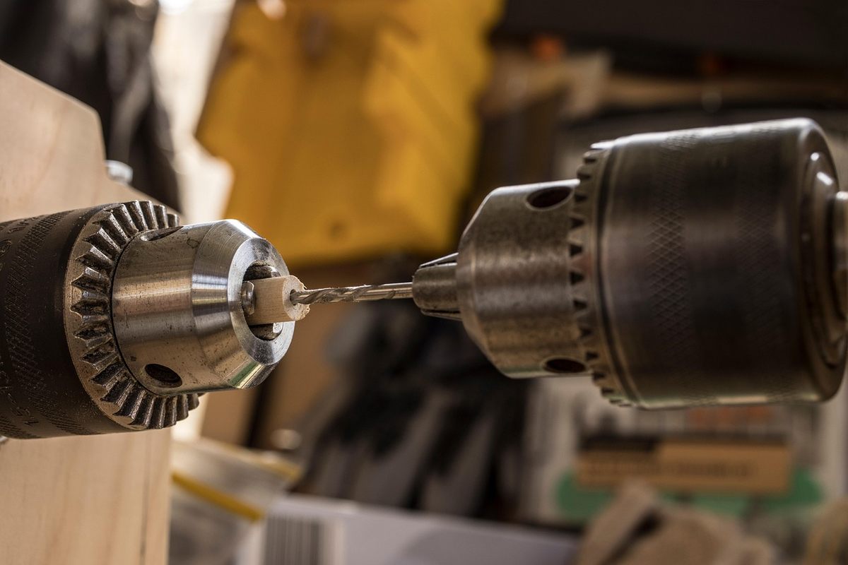 Perceuse vissant une vis dans un bois, atelier, outils autour