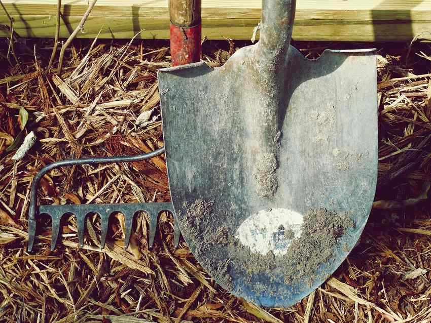 Pelle de jardin posée sur du paillis et de la paille sèche