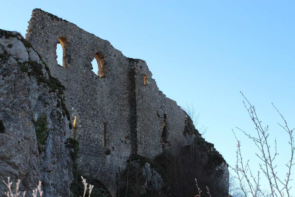 Ruines d'un château médiéval en pierre avec deux fenêtres gothiques sous ciel bleu